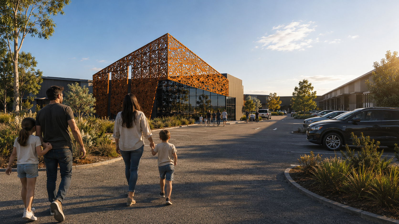 Family walking into Precinct Shoalhaven, with the Corten showroom, landscaped parking and warehouse rows beyond